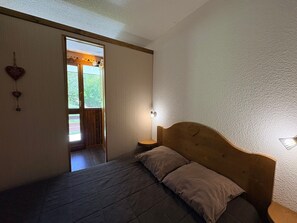 Un dormitorio con una cama de madera, una ventana con cortinas y vistas a la vegetación.