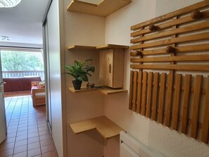 A room with a wooden slat wall, a potted plant, and a bed with a view to an outdoor balcony.
