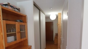 A hallway with a wooden cabinet, a sliding door, and a tiled floor. - Cozy studio with slopes access, shuttle and parking. For 4 guests. (La Salle-les-Alpes)
