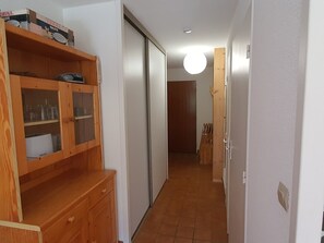 Un corridoio con un armadio in legno, una porta scorrevole e un pavimento piastrellato.