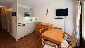 A compact kitchen with a microwave, sink, and wooden dining table with chairs. - Cozy studio with slopes access, shuttle and parking. For 4 guests. (La Salle-les-Alpes)