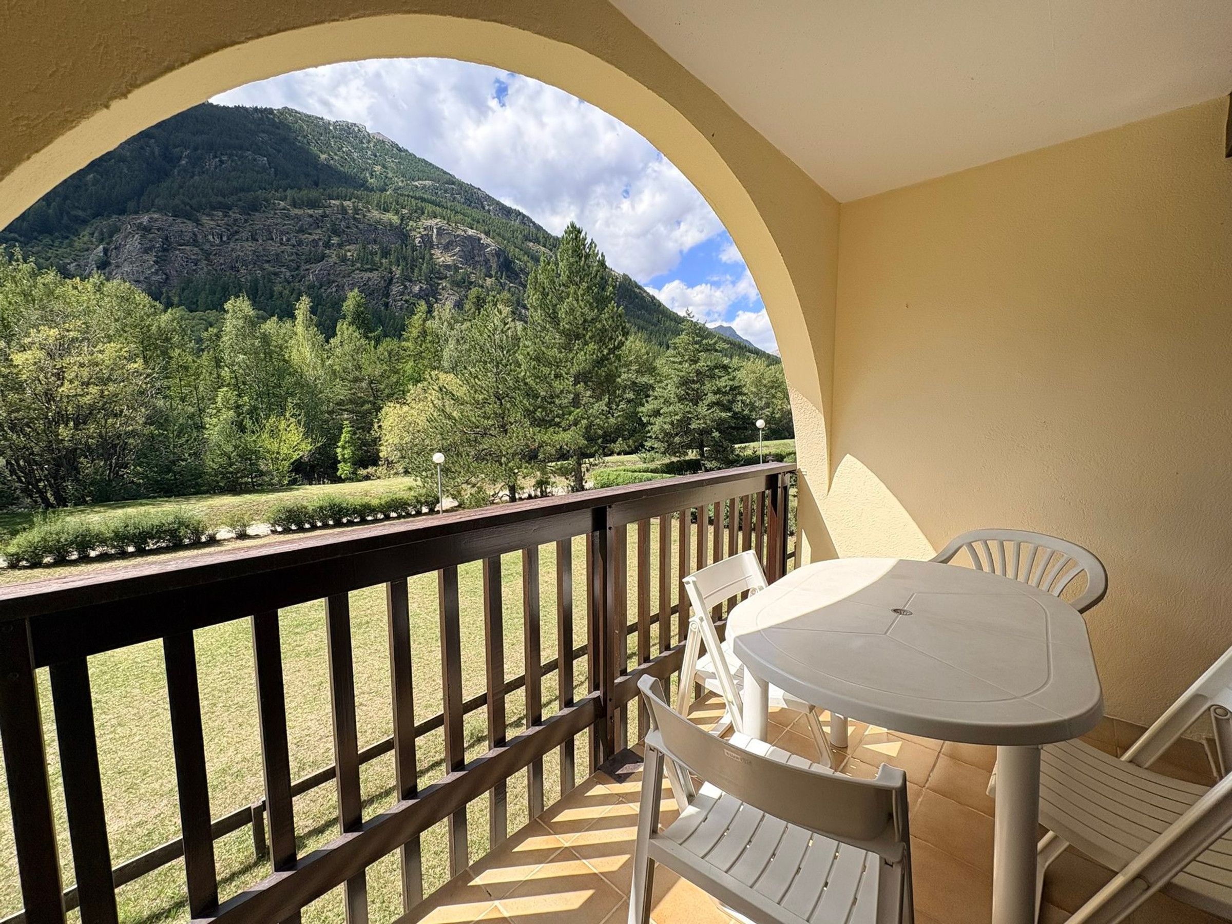 Un balcon donnant sur un paysage montagneux, avec une table et deux chaises.
