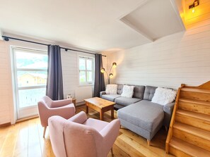 A modern living room with a sofa, two chairs, a coffee table, and a staircase.