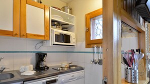 A compact kitchen with wooden cabinets, a microwave, a coffee maker, and a dishwasher. - Functional studio at the foot of the slopes for 3/4 people, balcony, divisible living (Belle Plagne)
