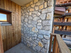 A corner of a building with a stone wall and wooden paneling.