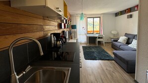 Un espacio habitable compacto con cocina, comedor y sofá.