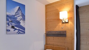 A small wooden room with a bed, a wall-mounted light, and a painting of a mountain. - Renovated cozy apartment near slopes, 3 rooms + cabin for 8 people, pets allowed (Plagne Bellecôte)
