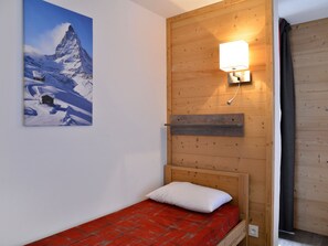 Ein kleiner Holzraum mit einem Bett, einer Wandleuchte und einem Berg.