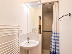 Bathroom features a clean, minimalist design with a white sink, mirror, and shower.