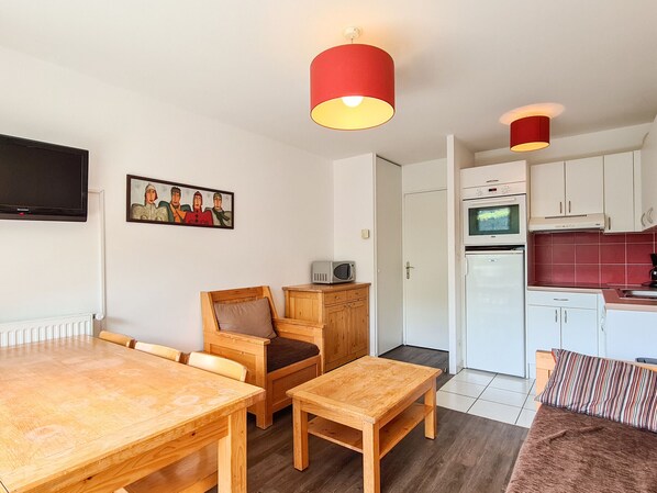Cozy living space with a dining table, kitchenette, and mounted TV.
