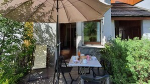 Une terrasse extérieure avec une table et des chaises, un grand parasol et une plateforme en bois.