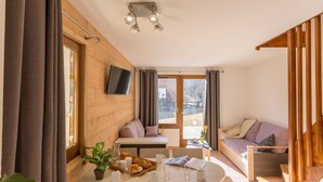 Une pièce chaleureuse comprenant une table à manger, des chaises, un canapé et un téléviseur fixé au mur.