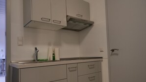 A kitchen with white cabinets, a stainless steel sink, and a range hood. - Pfalzzeit - Der Wald (Weisenheim am Berg)