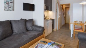 A compact living space with a sofa, a small kitchen area, and a dining table. - Renovated apartment at slopes with balcony (Belle Plagne)