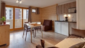 Un espacio habitable compacto con comedor, kitchenette y sofá.
