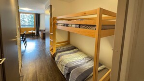 Una habitación pequeña con literas, un escritorio y una silla.