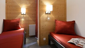 Ein kleiner, gemütlicher Raum mit zwei Betten, Holzwänden und zwei Wandleuchten.