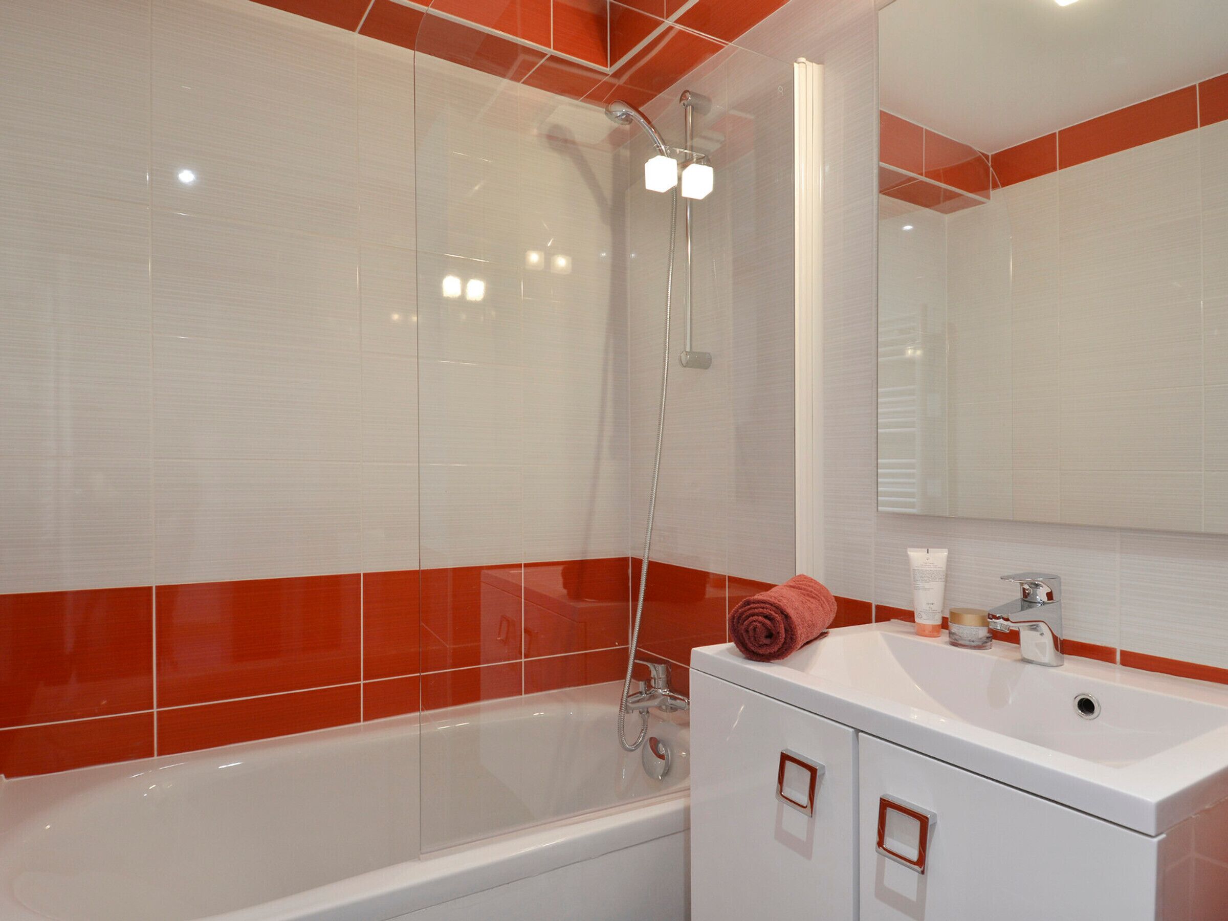 A modern bathroom with a white bathtub, a shower with a glass enclosure, and a vanity with a mirror.