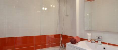 A modern bathroom with a white bathtub, a shower with a glass enclosure, and a vanity with a mirror.