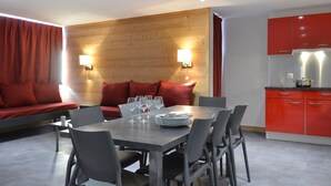 Ein moderner Essbereich mit einer Wandpaneele aus Holz, roten Kissen und einer Küche mit roten Schränken.