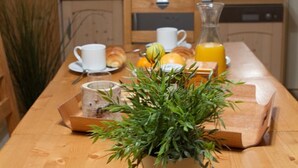 A breakfast table with a tray of fresh herbs, a glass of orange juice, a croissant, and a cup of coffee. - Comfortable studio near slopes, Free Wifi, Pets allowed (Briançon)
