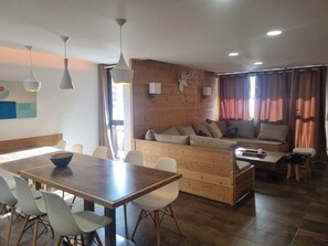 Una sala acogedora con un sofá de madera, una mesa de comedor con sillas y una mesa de centro.