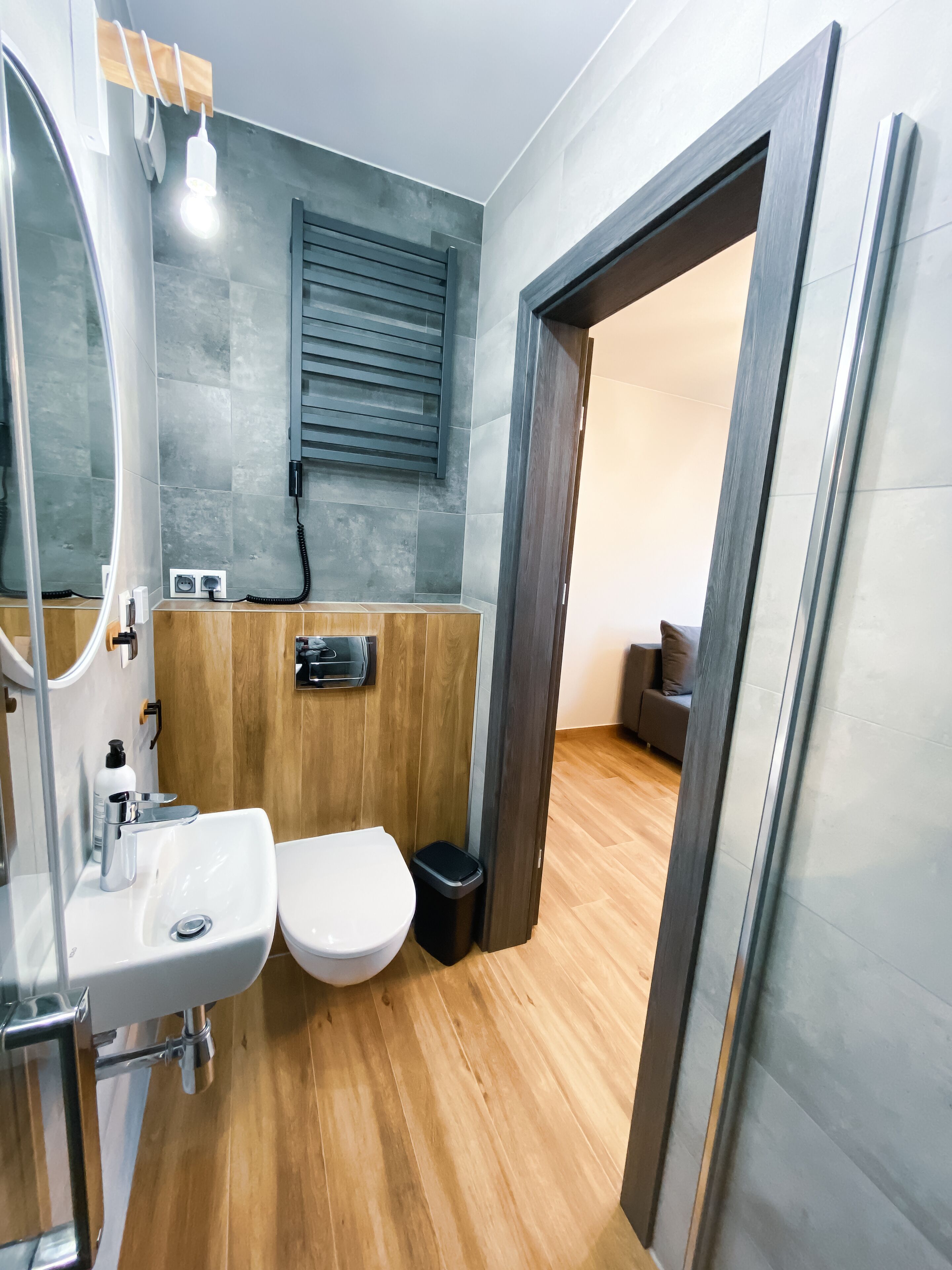Un bagno moderno con un mobile bagno in legno, un lavabo bianco e un water.