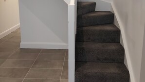 Una escalera con barandillas blancas y peldaños alfombrados oscuros.