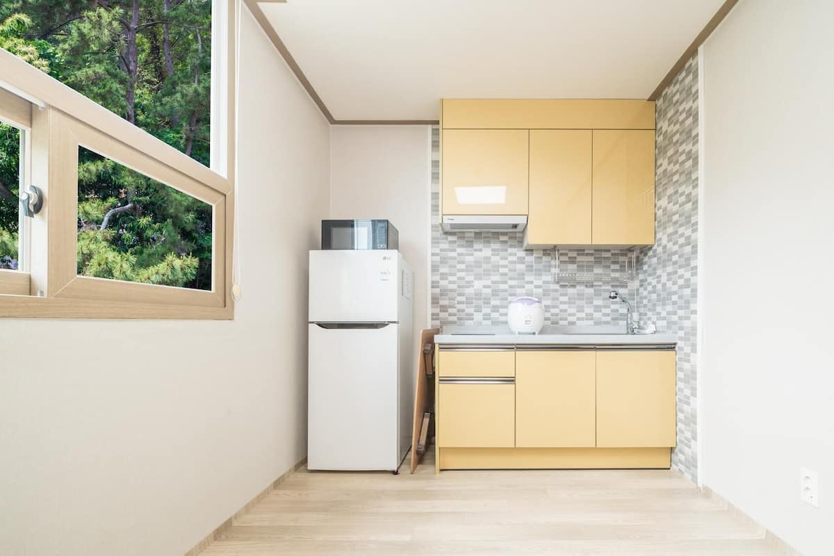 A compact kitchen with a refrigerator, microwave, and a tiled backsplash.
