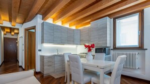 Una cocina moderna con armarios blancos, una mesa de comedor con cuatro sillas y un ventanal que proporciona luz natural.