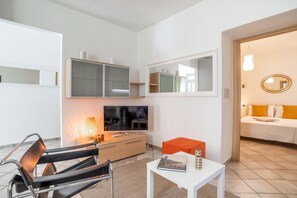 Un salon moderne comprenant un canapé, un téléviseur, une table basse et un coin repas avec une chaise et une table.