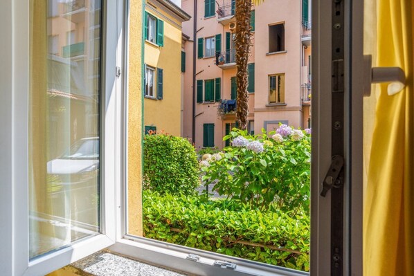 A window view of a building with balconies, greenery, and a yellow curtain.