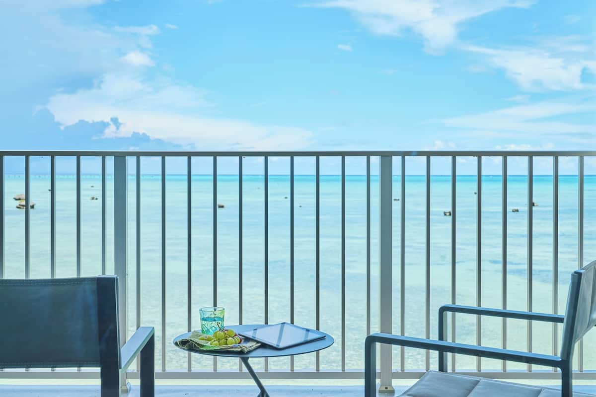 Ein Balkon mit Tisch, Stühlen und Blick aufs Meer.