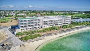 Un hotel moderno con varios pisos, una piscina en la azotea y ubicación frente a la playa.