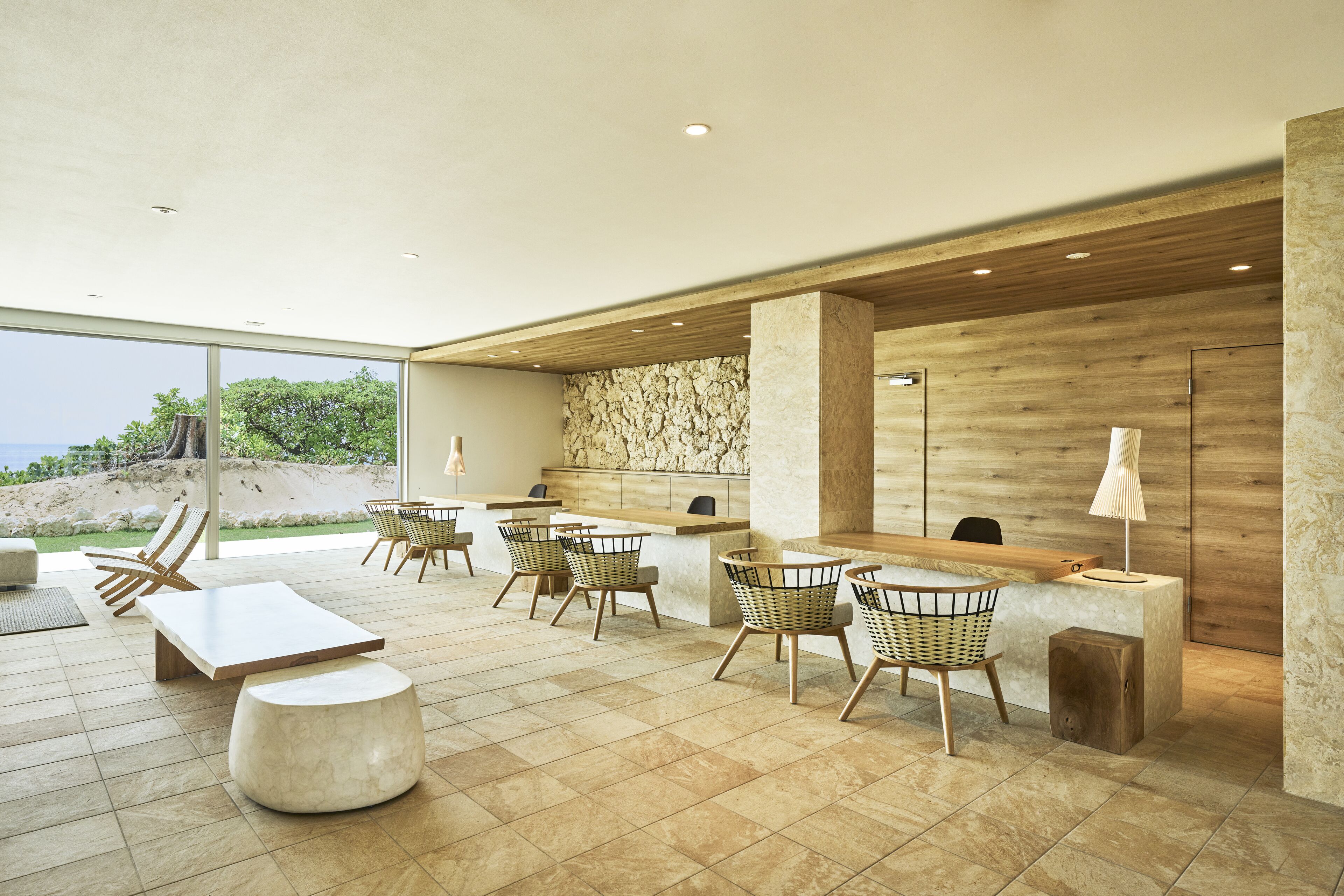A modern indoor space with a reception desk, seating area, and a view of the outdoors.