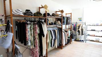 Un magasin de vêtements où l’on trouve des étagères remplies de vêtements et de chapeaux.