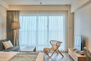Hotellihuone, jossa on sänky, tuoli, työpöytä, lamppu ja televisio.