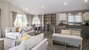 A spacious living area with a sofa set, a dining table, and a kitchenette. - Parkers Place (Carnforth)