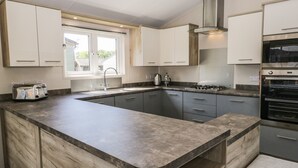 A modern kitchen with a large island, built-in appliances, and ample counter space. - Parkers Place (Carnforth)
