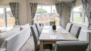 A modern dining area with a long table, grey upholstered benches, and a vase with white flowers. - Parkers Place (Carnforth)