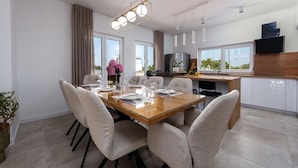 A modern dining area with a wooden table, six chairs, and a chandelier. - Villa Dora Zadarvillas (Policnik)