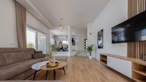 A modern living room with a brown sofa, a coffee table, and a TV mounted on the wall. - Villa Dora Zadarvillas (Policnik)