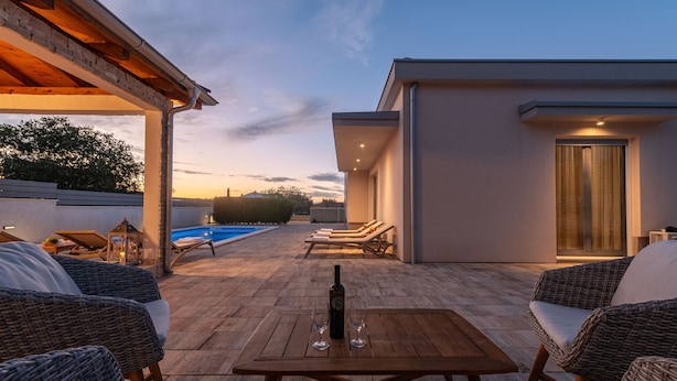 A rooftop terrace with wicker furniture, a pool, and a modern building in the background. - Villa Dora Zadarvillas (Policnik)