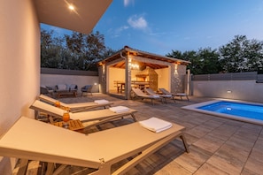 A poolside area with lounge chairs, a small covered seating area, and a stone-tiled floor. - Villa Dora Zadarvillas (Policnik)
