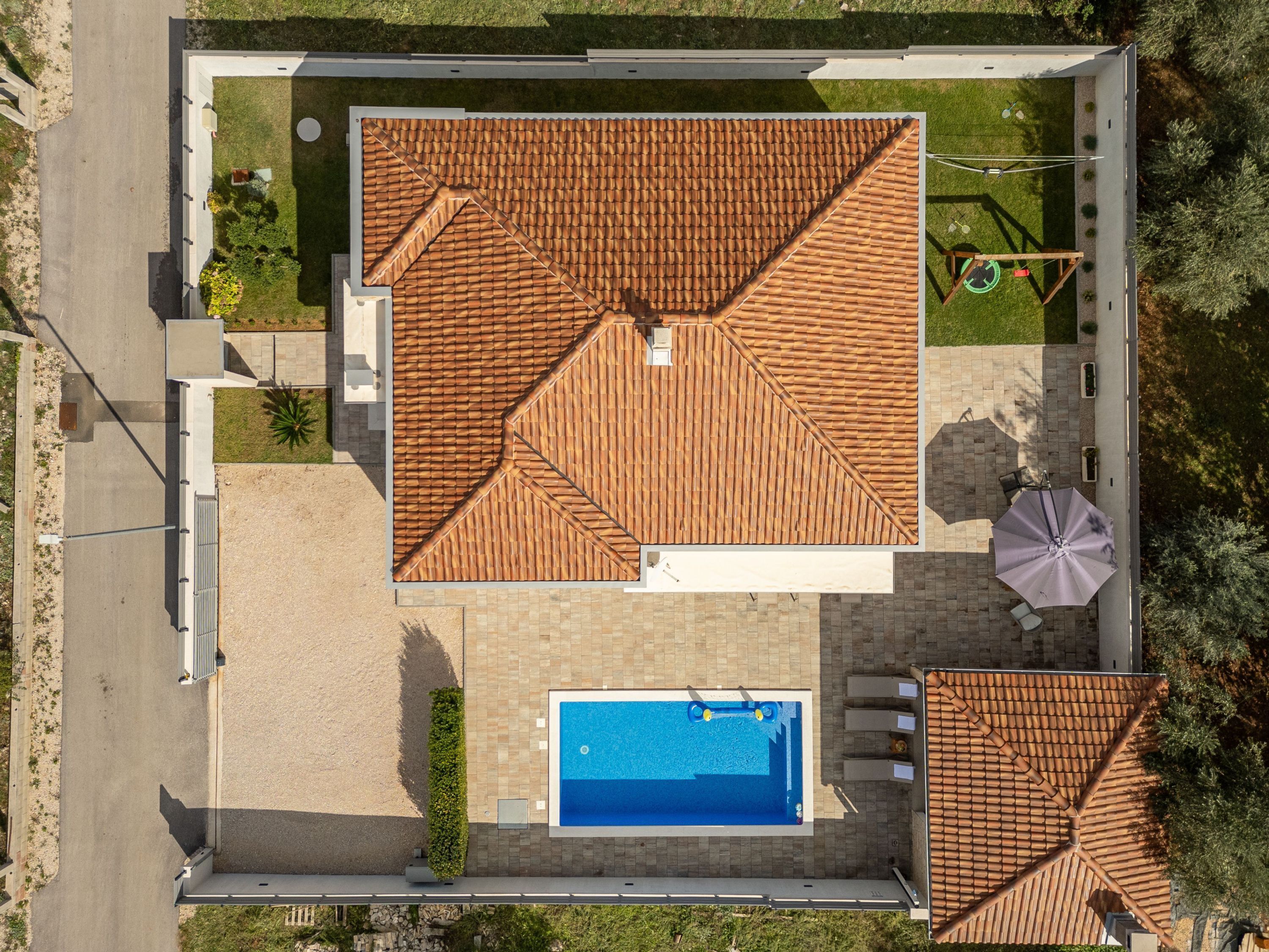 An aerial view of a property with a tiled roof, a swimming pool, and outdoor seating.