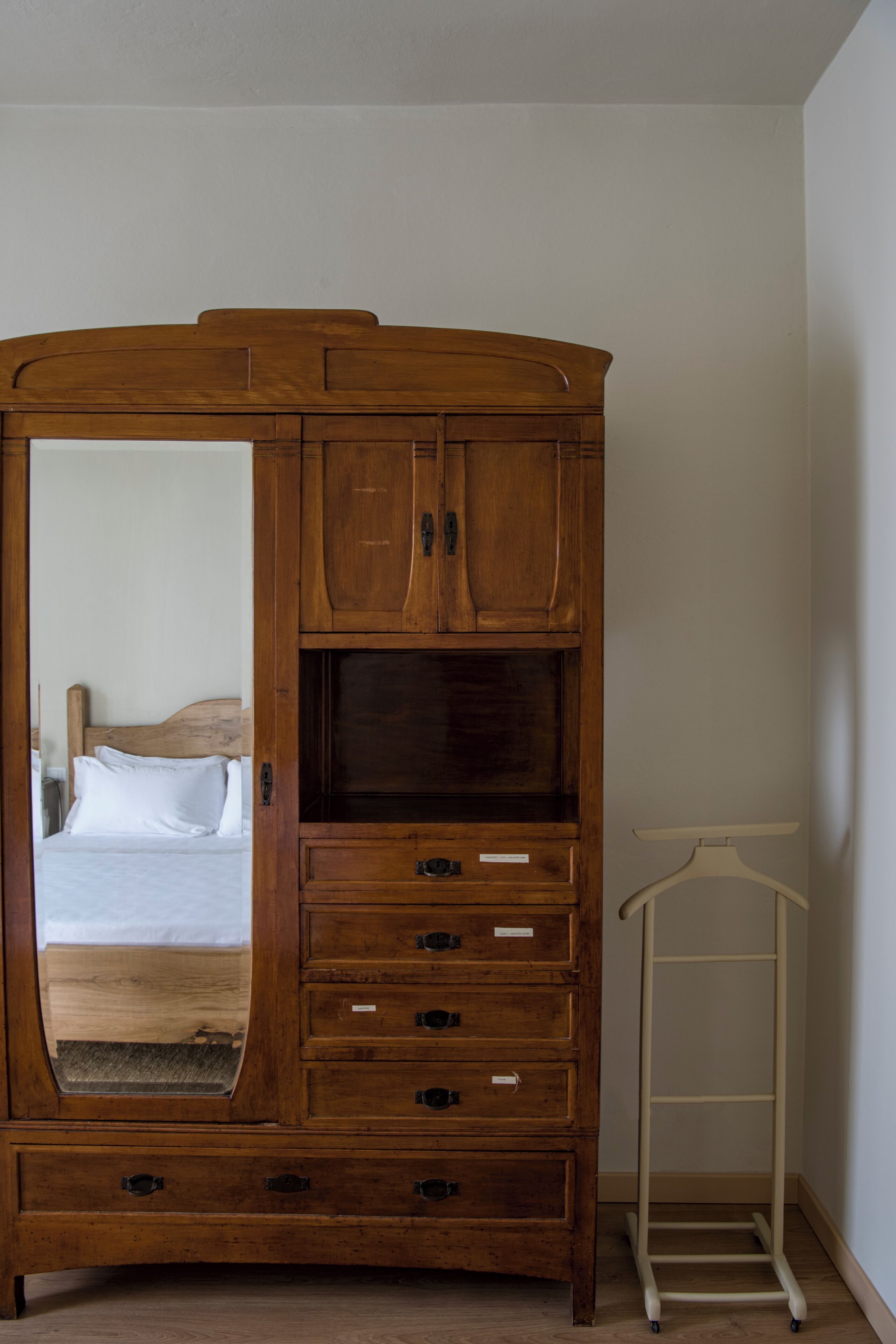 Un armario de madera con espejo, cajones y barra para colgar ropa.