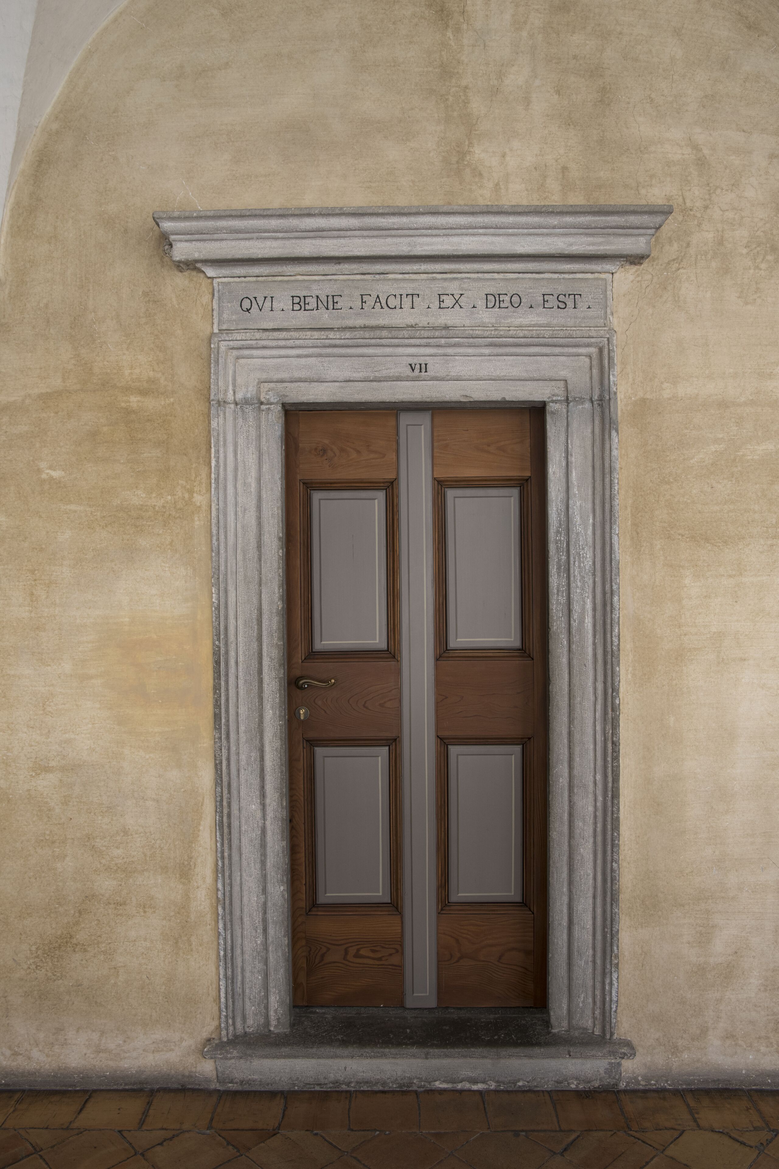 Une porte au style classique, encadrée de deux colonnes et surmontée d’un linteau décoratif.