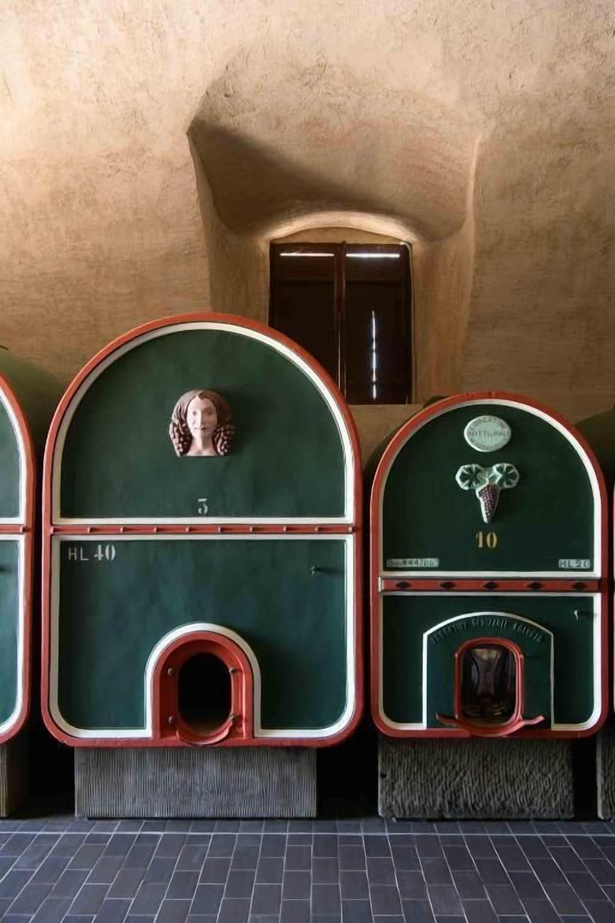 Fila de antiguos baños públicos con detalles en verde y rojo, numerados 5 y 10, y una pequeña ventana en la parte superior.