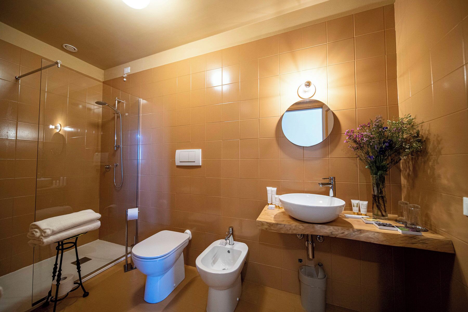 Un baño con ducha envuelta en vidrio, inodoro, bidé y lavamanos con espejo.