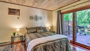 Een slaapkamer met een groot bed, twee nachtkastjes met lampen, een decoratief muurkunstwerk en een glazen schuifdeur die leidt naar een terras.